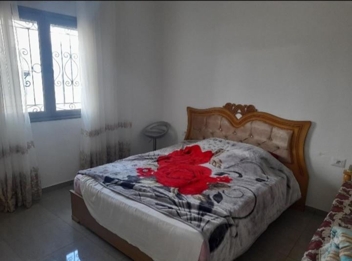 ミドゥンにあるappartement douha Midounの赤い花が寝室のベッドに敷かれている