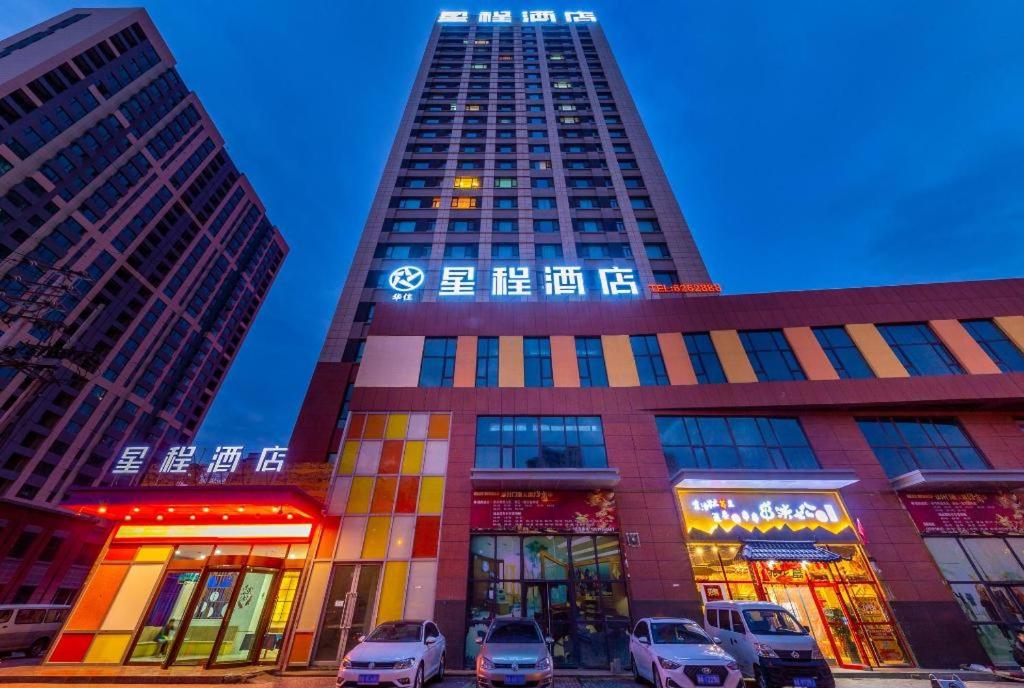 a tall building with cars parked in front of it at Starway Hotel Xining Chengbei Wanda Plaza in Xining