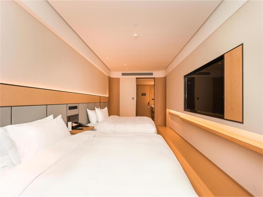 um quarto de hotel com duas camas e uma televisão de ecrã plano em Ji Hotel Nanjing Baijia Lake em Jiangning
