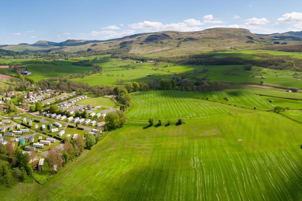 an aerial view of a green field with houses at Campsie Glen Holiday Park in Glasgow