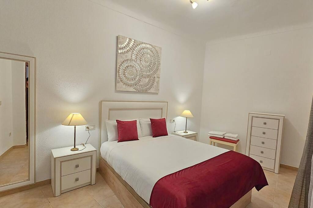 een slaapkamer met een groot bed met rode kussens bij Aloreña con balcones al Real in Úbeda