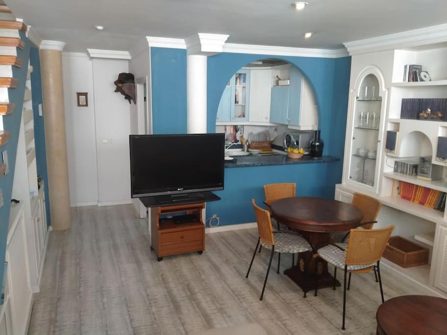 uma sala de estar com televisão e uma mesa com cadeiras em Duplex entero con garaje privado y terraza em Albacete