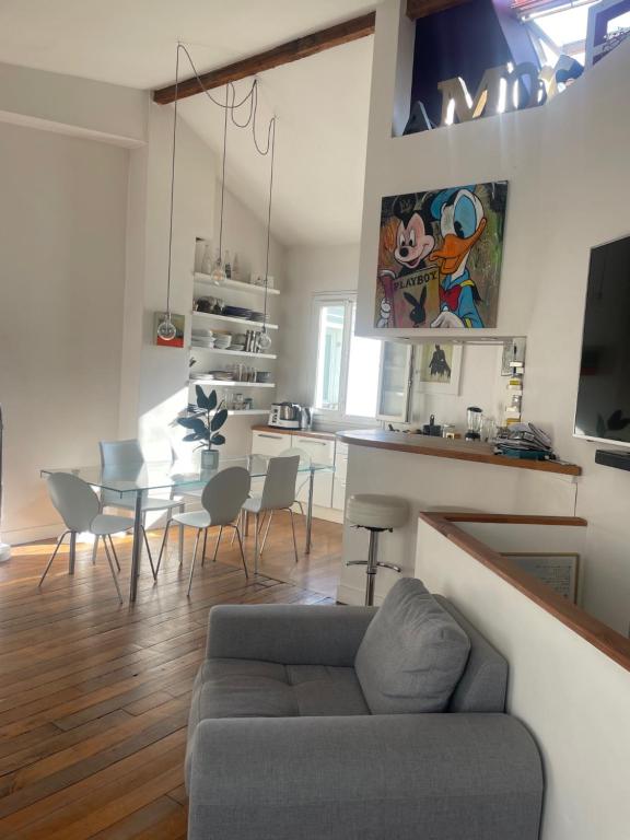 un salon avec un canapé et une table avec des chaises dans l'établissement Un loft proche Bastille pour Paris 2024, à Paris