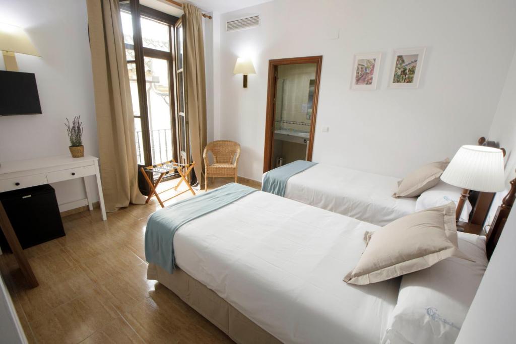 um quarto de hotel com duas camas e uma secretária em Hotel San Miguel em Córdoba