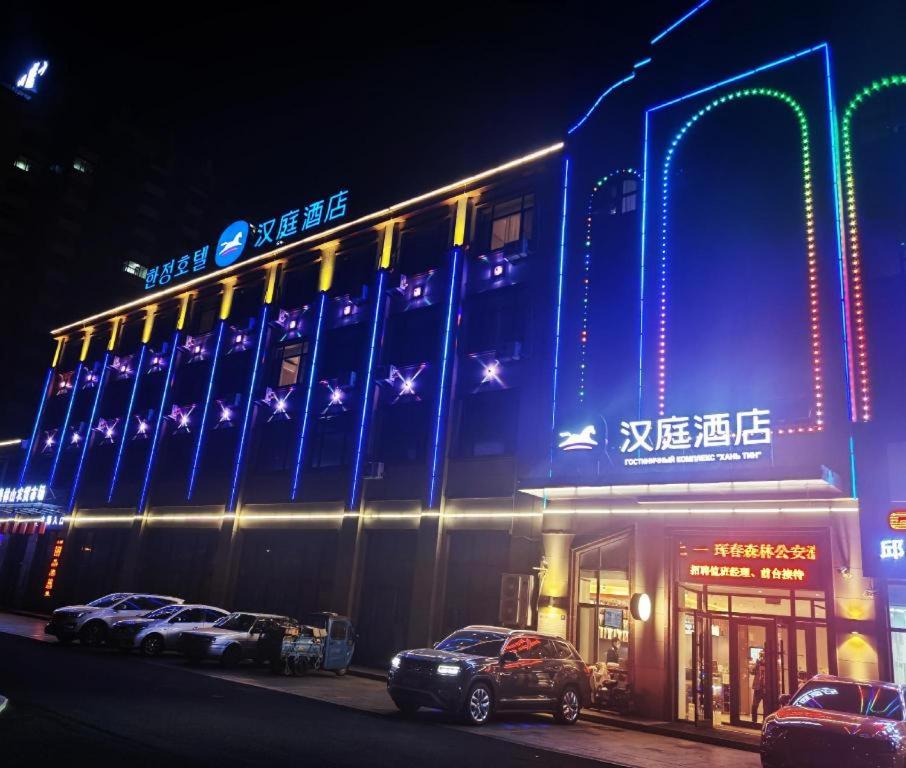 um edifício com carros estacionados em frente a ele à noite em Hanting Hotel Hunchun Railway Station em Hunchun