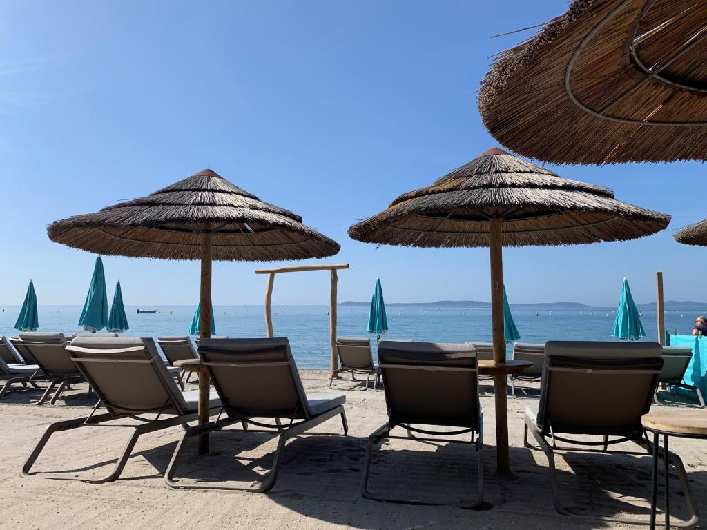 a group of chairs and umbrellas on a beach at Hôtel La Villa Douce in Rayol-Canadel-sur-Mer