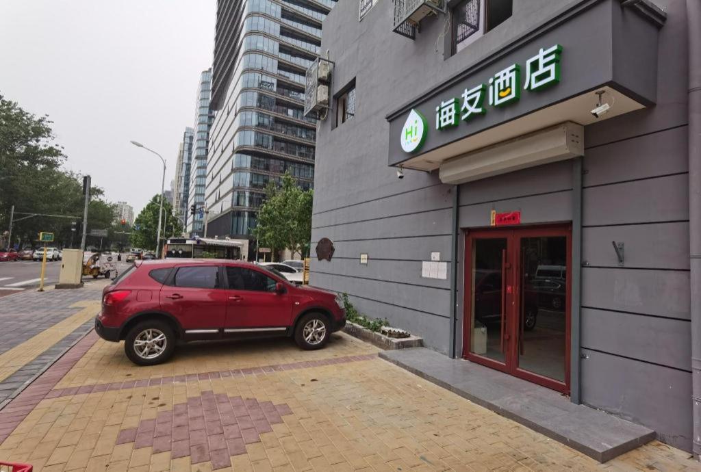 Hi Inn Beijing Chaoyangmen في بكين: سيارة حمراء متوقفة أمام مبنى