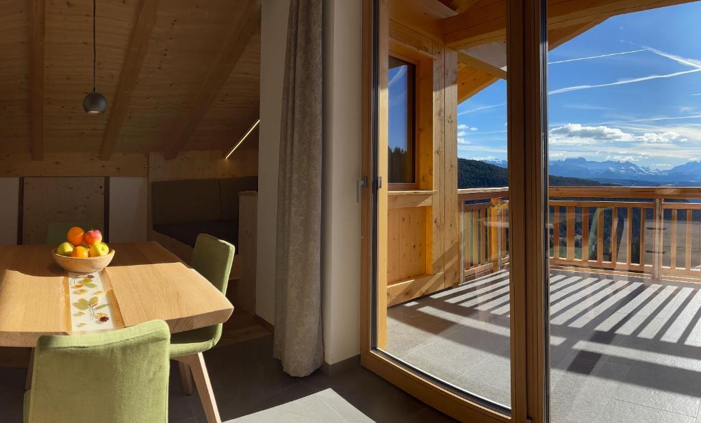 een kamer met een tafel en een balkon met uitzicht bij Moserhof Wohnung Salbei in Meltina