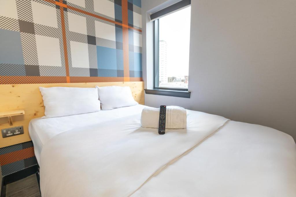 a bedroom with a white bed with a book on it at easyHotel Glasgow City in Glasgow