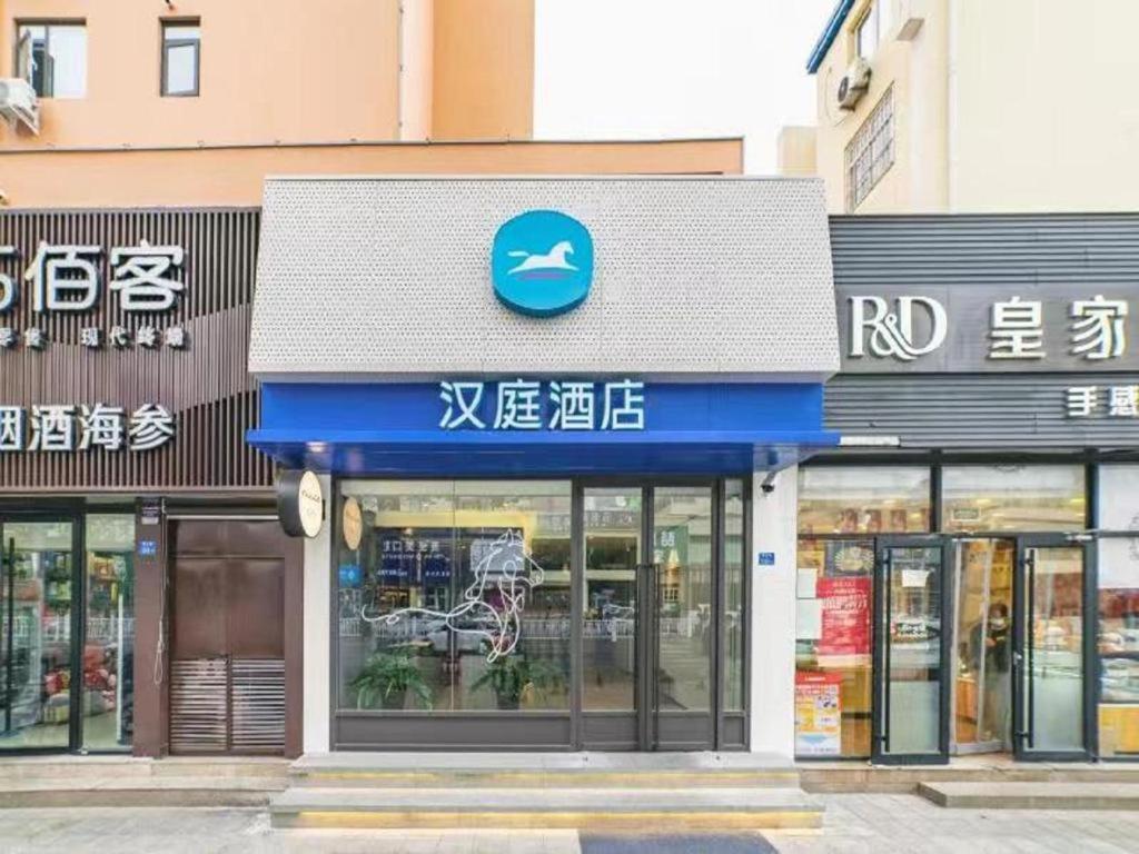 un magasin avec un panneau bleu sur le côté d'un bâtiment dans l'établissement Hanting Hotel Qingdao Nanjing Road, à Fushansuo