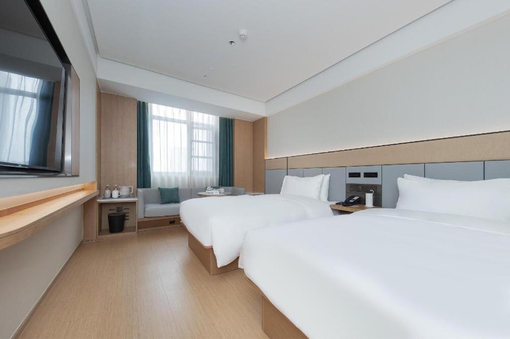 a hotel room with two beds and a television at Ji Hotel Wuhan Jiedaokou in Han-yang-hsien