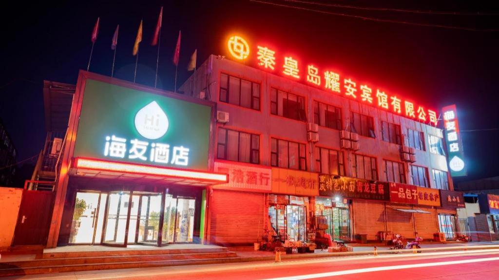 ein Gebäude mit Neonschildern in der Nacht auf einer Straße in der Unterkunft Hi Inn Qinhuangdao Railway Station in Qianmafang