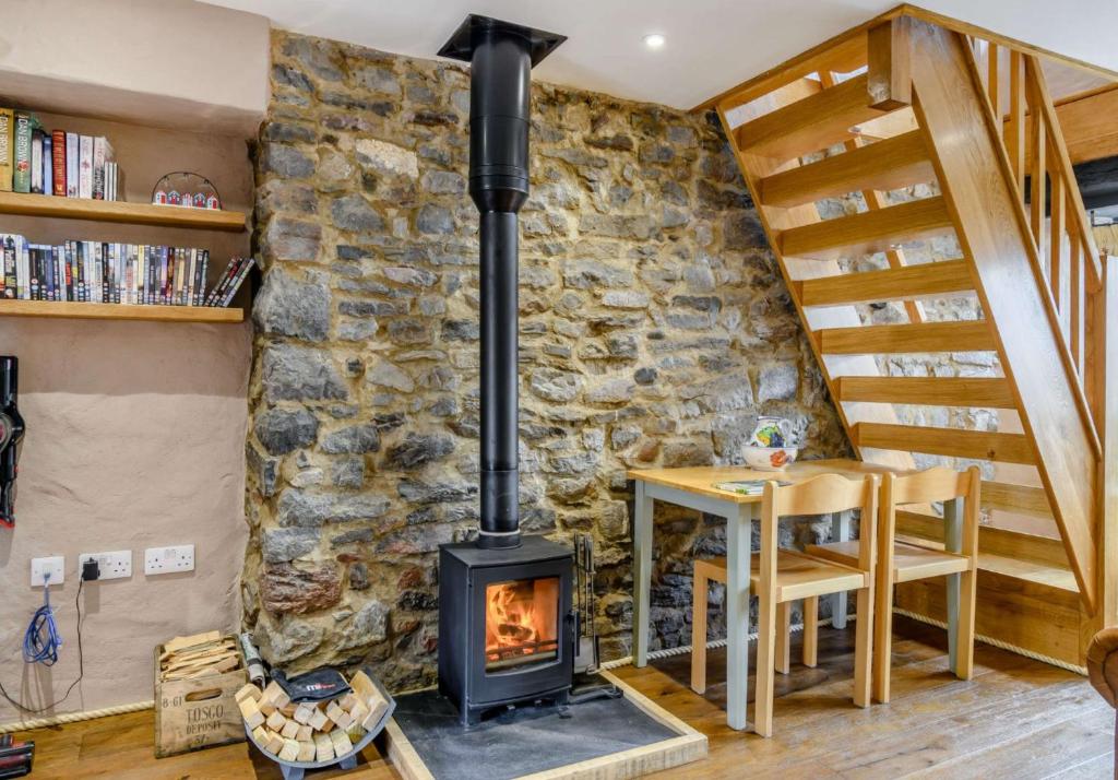 a wood stove in a living room with a stone wall at Stable Cottage in Pembroke