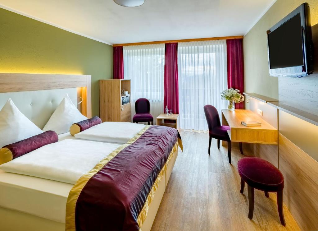 フロイデンシュタットにあるHotel Schwarzwald Freudenstadtのベッドとデスクが備わるホテルルームです。