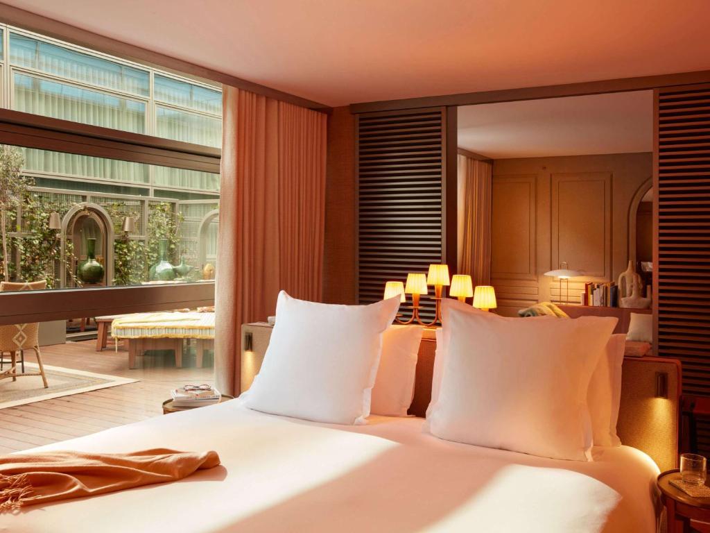 een slaapkamer met een groot bed en een groot raam bij Mondrian Bordeaux Les Carmes in Bordeaux