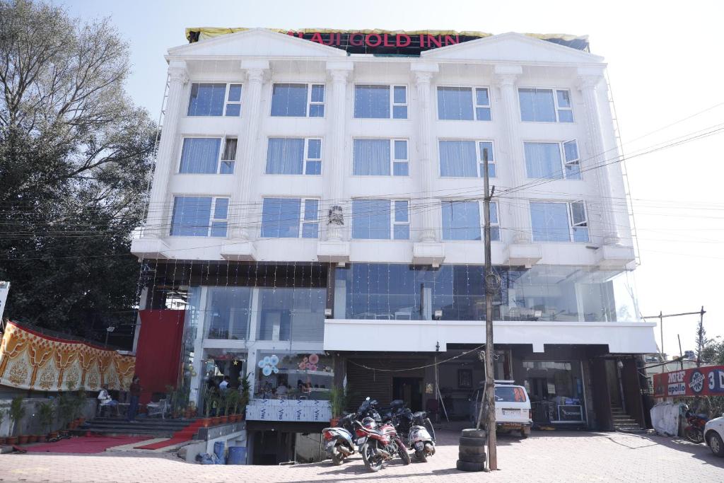 Biały budynek z motocyklami zaparkowanymi przed nim w obiekcie Balaji gold inn hotel w mieście Hubballi-Dharwar