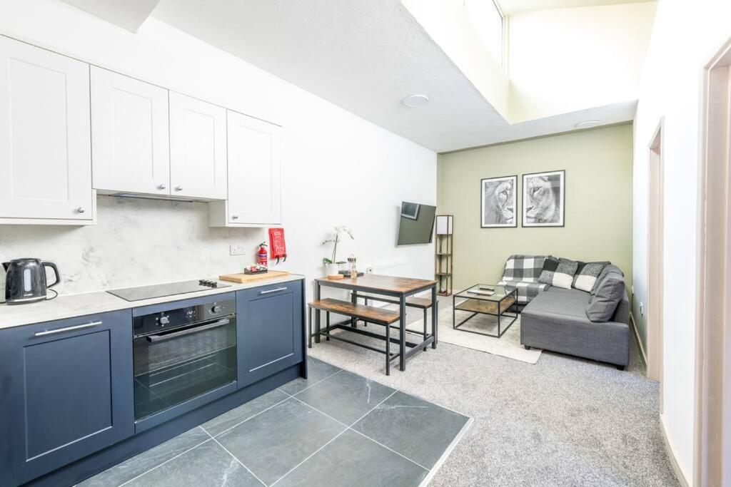 a kitchen with blue cabinets and a living room at Newly Renovated Upnor House with 2 Free Parking by Prescott Apartments in Bristol