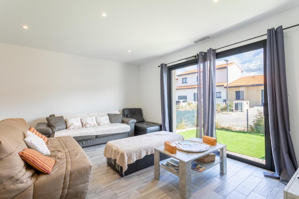 een woonkamer met een bank en een groot raam bij Rascola villa piscine 4 étoiles in Le Boulou