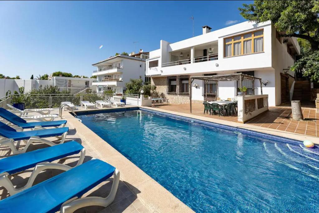 uma piscina com cadeiras e uma casa em Villa los Dragos em Santa Ponsa