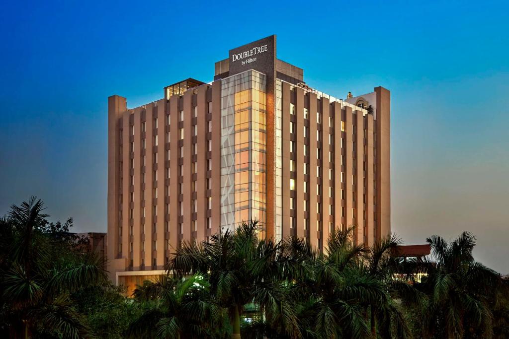a large building with palm trees in front of it at DoubleTree by Hilton Gurugram Baani Square in Gurgaon