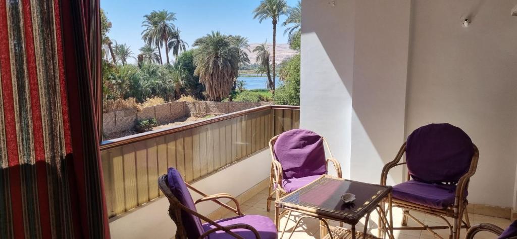 two chairs and a table on a balcony with a view at Abo Hisham Nile Flat in Luxor