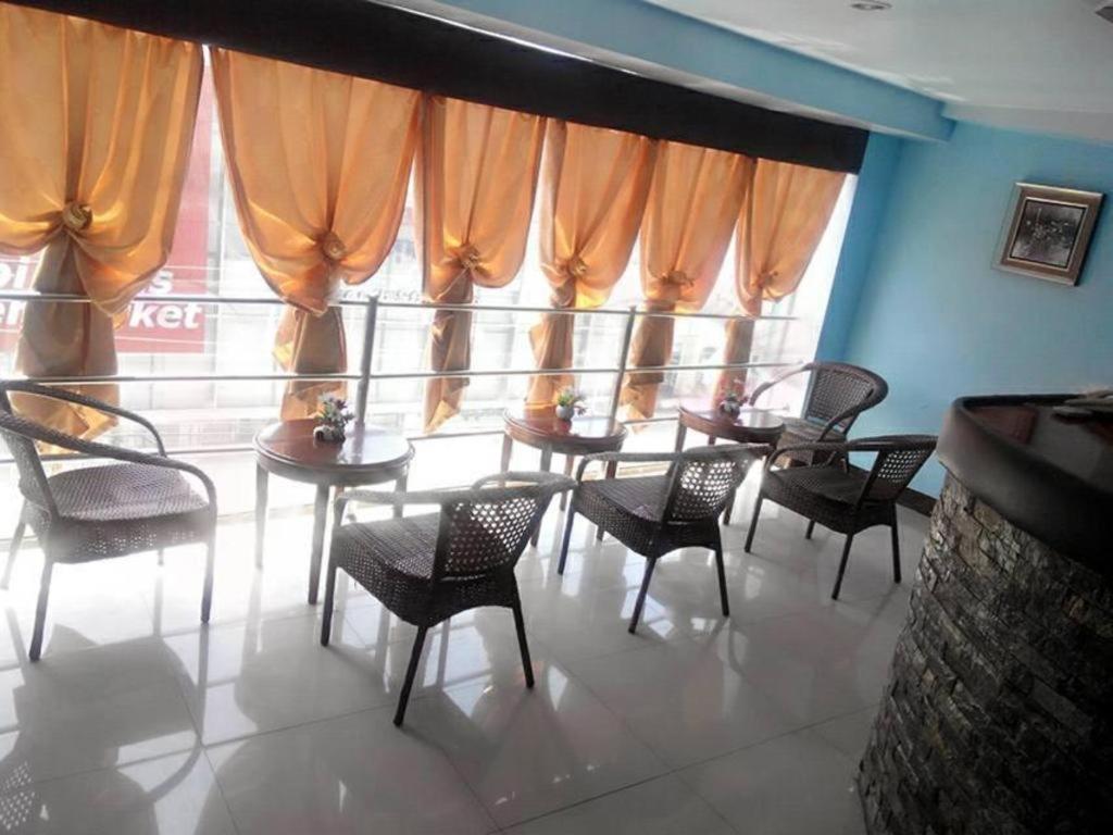 een eetkamer met tafels en stoelen en een groot raam bij Asia Novo Boutique Hotel-Dumaguete in Dumaguete