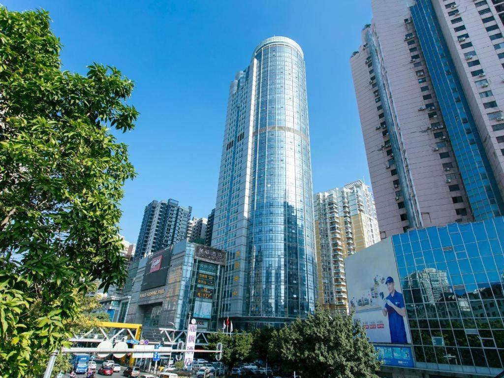 Lavande Hotel Huizhou World Trade Center في هويزو: مبنى زجاجي طويل في مدينة ذات مباني طويلة