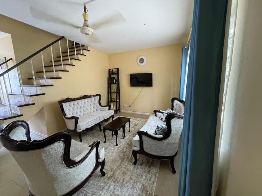 a living room with chairs and a couch and stairs at Tudor Court in Mombasa