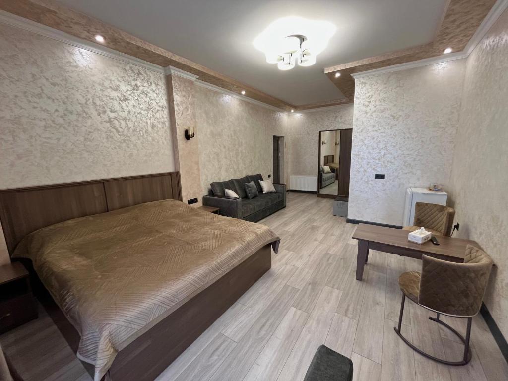 a bedroom with a bed and a couch and a table at Amroc Hotel - Հյուրանոց Ամրոց in Noyemberyan