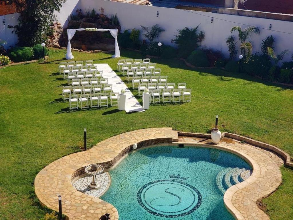 eine Hochzeit im Freien mit einem Pool und Stühlen in der Unterkunft Selborne Hotel in Bulawayo