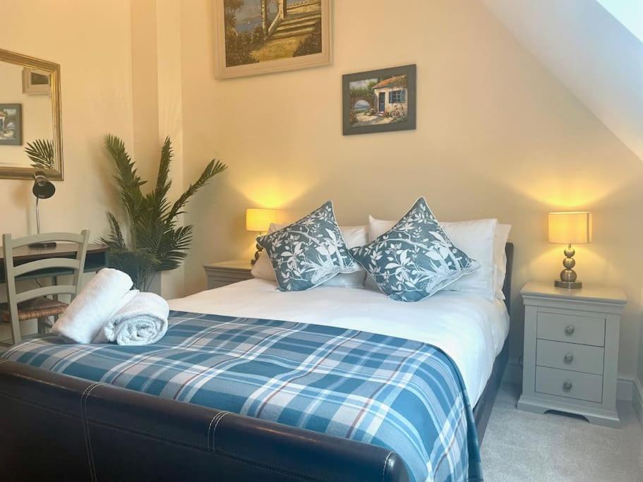 Luxury Country Bolthole Near Soho Farmhouse في Middle Barton: غرفة نوم مع سرير ووسائد زرقاء وبيضاء