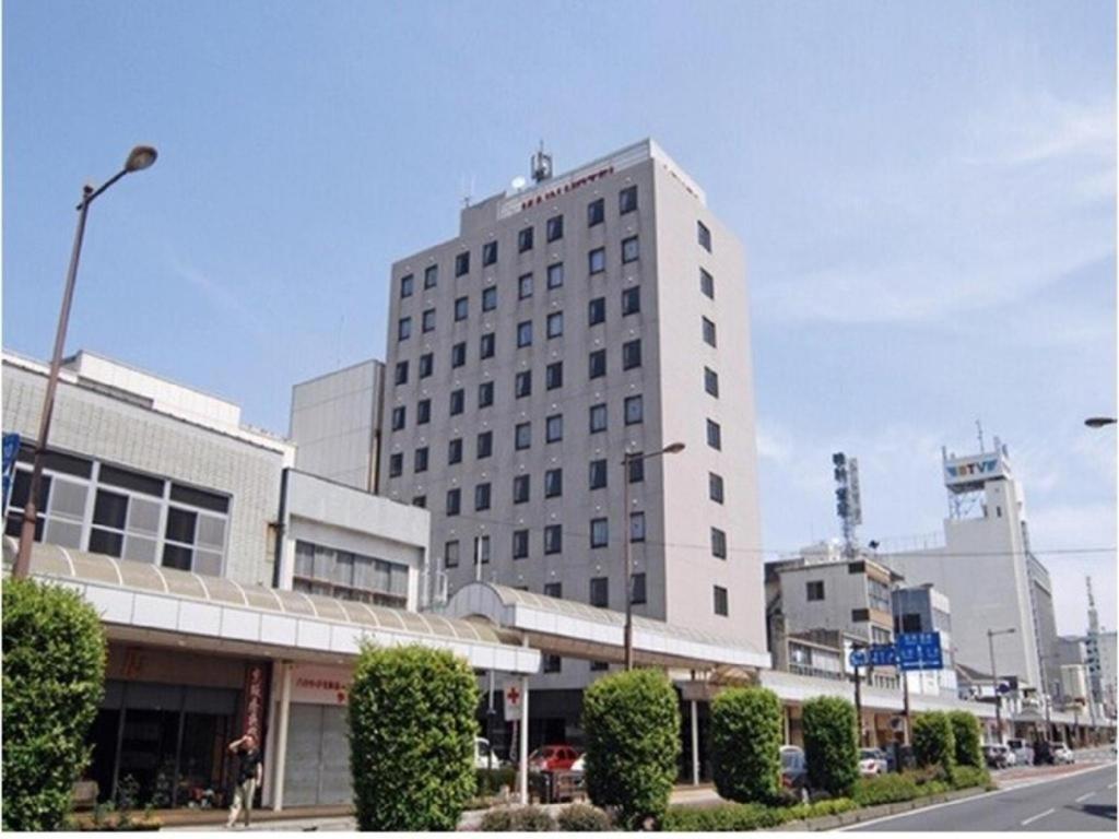 een hoog wit gebouw in een stadsstraat bij Main Hotel in Miyakonojo