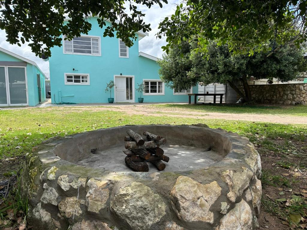 a stone fire pit in front of a blue house at Die Blou Huis in Stilbaai