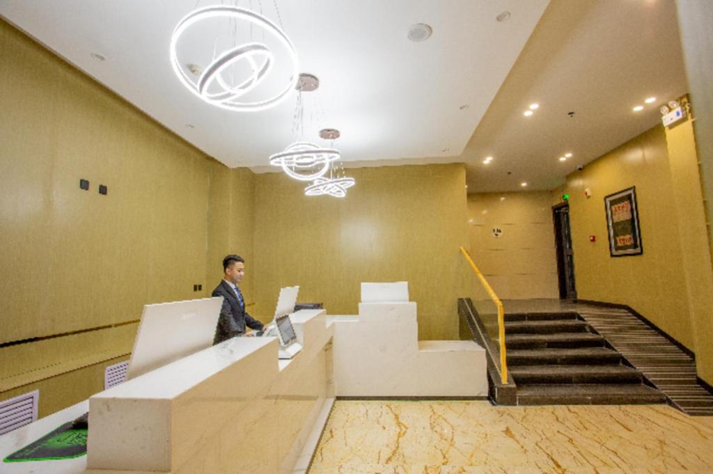 a man standing in an office with a laptop at City Comfort Inn Xining Limeng Commercial Pedestrian Street in Xining