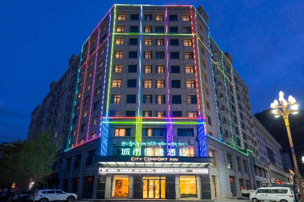 un edificio con luces de colores en el costado. en City Comfort Inn Shannan Passenger Terminal en Nedong