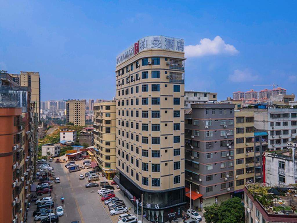 un edificio blanco alto en una ciudad con coches en Borrman Hotel Wuzhou Teng County, en Tengcheng