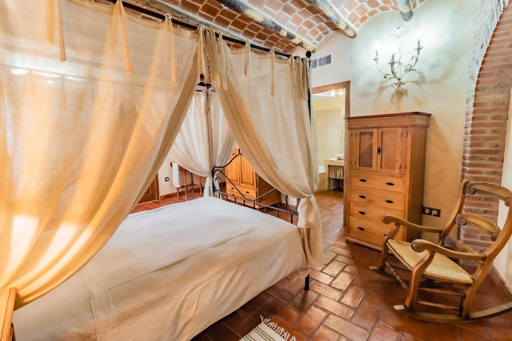 a bedroom with a canopy bed and a chair at Hotel Rural La Sinforosa in Alange