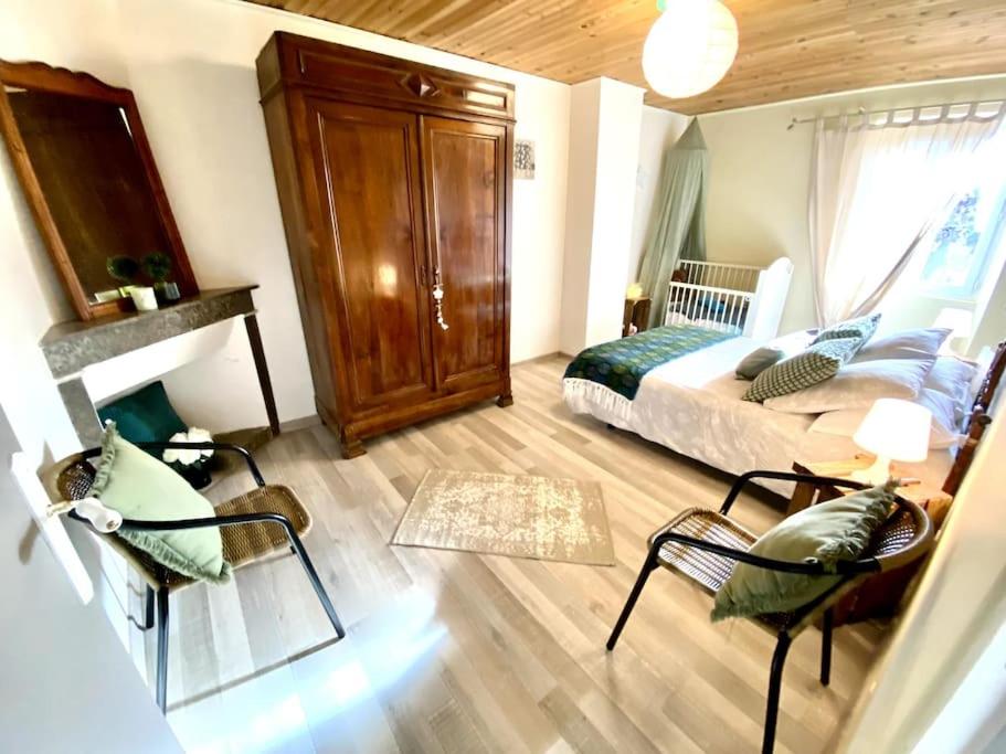 une chambre avec un lit et des chaises dans une pièce dans l'établissement La ferme de mon grand-pėre, Gîte les Bourriaux 6p 3ch, à Saint-Pons