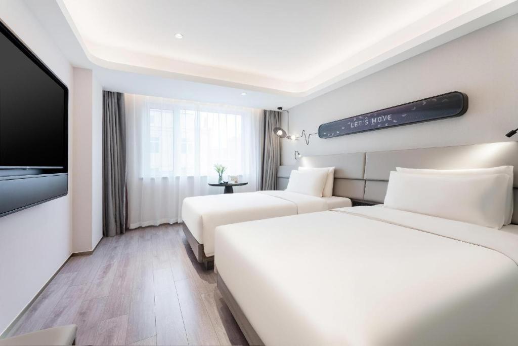 Cette chambre comprend 2 lits et une télévision à écran plat. dans l'établissement Atour Light Hotel Dalian Xinghai Plaza Xi'an Road, à Dalian