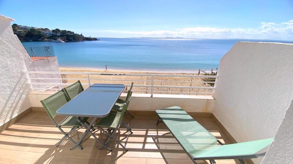 een tafel en stoelen op een balkon met uitzicht op het strand bij Verones 1b in Roses