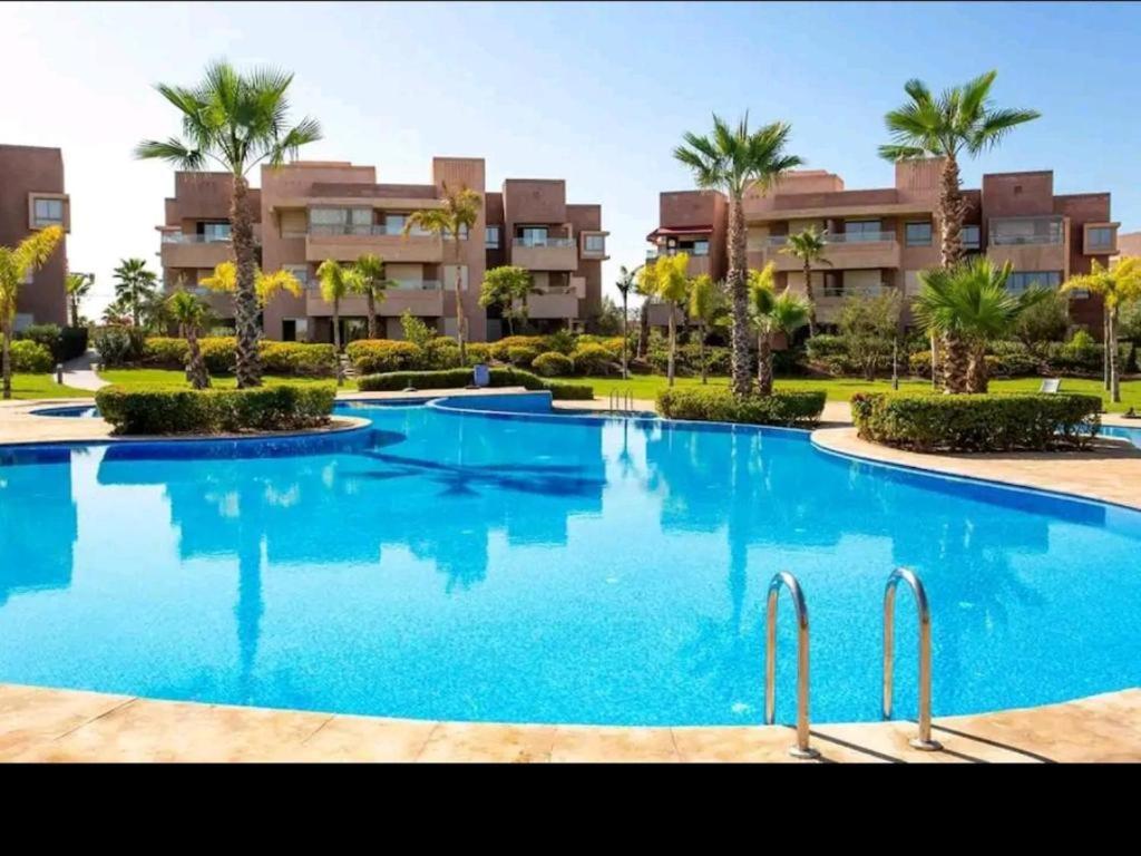 a large swimming pool in a resort with palm trees at Golf City Prestigia - Exclusive Apartment in Marrakesh