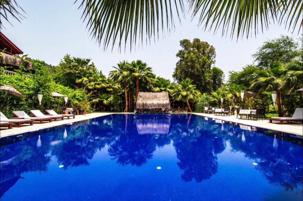 a pool at a resort with blue water and palm trees at Layla Gocek Adults only in Göcek