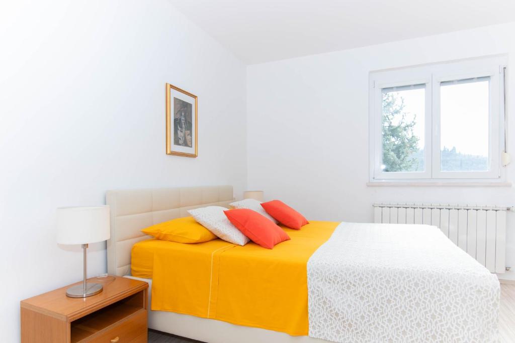 a white bedroom with a bed with yellow and red pillows at Apartment Nonna Laura in Portorož