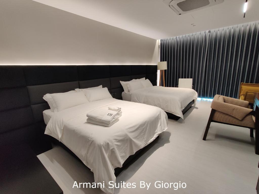 a hotel room with two beds and a chair at Subang Jaya Armani Soho in Subang Jaya