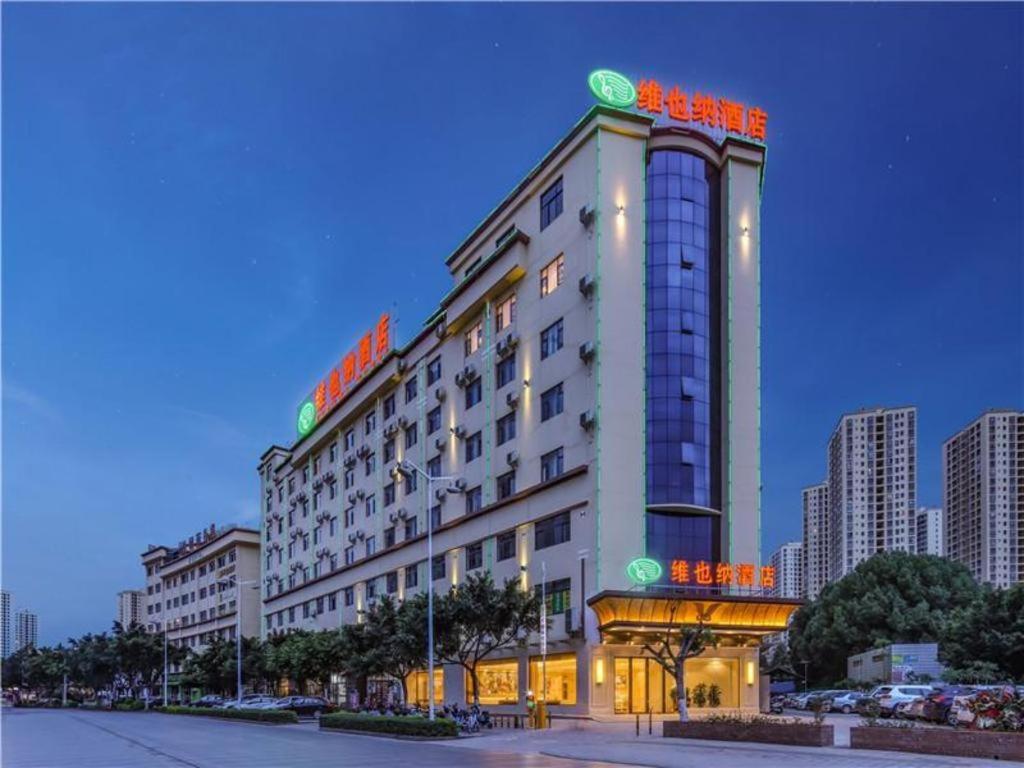 Vienna Hotel Yuxi Hongta Avenue High-Speed Railway Station في Yuxi: مبنى الفندق عليه لافتات برتقالية