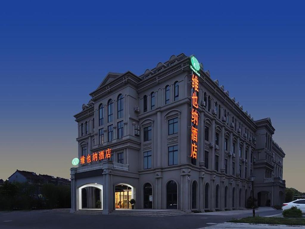 a large building with an orange sign on it at Vienna Hotel Zhejiang Tongxiang Puyuan in Tongxiang