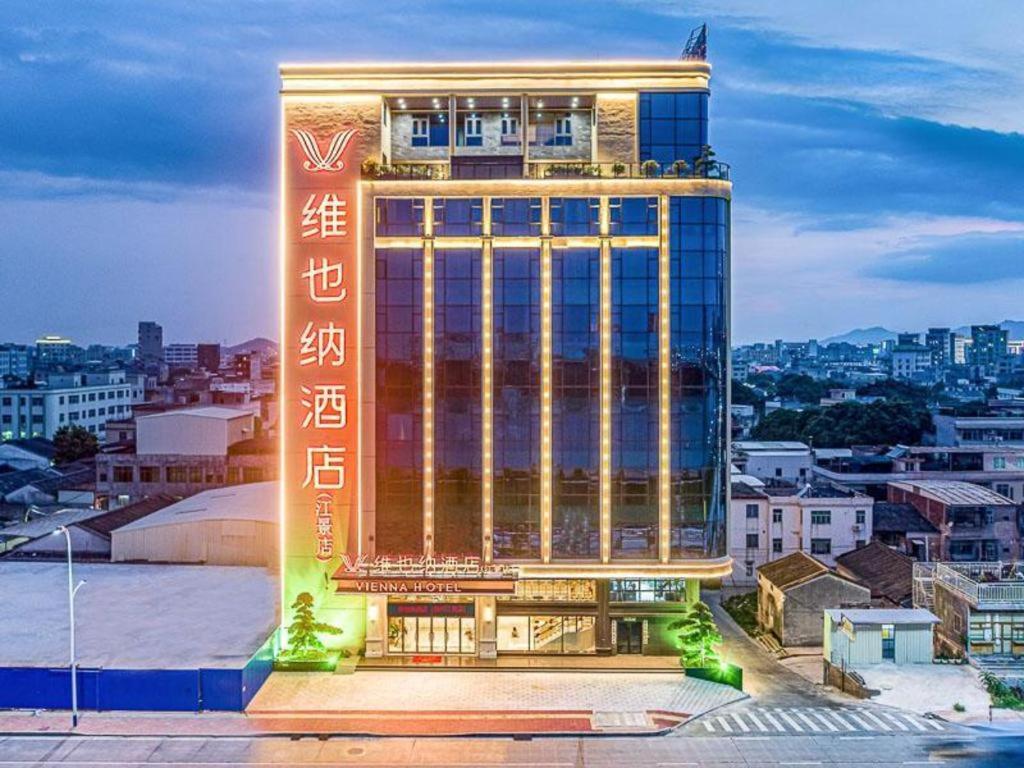 a tall building with a sign in front of it at Vienna Hotel Chaozhou River View in Chaozhou