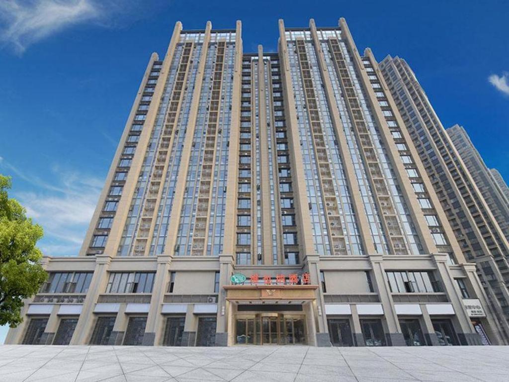 duży wysoki budynek z niebieskim niebem w tle w obiekcie Vienna Hotel Anhui Fuyang Chengnan New District w Fuyang