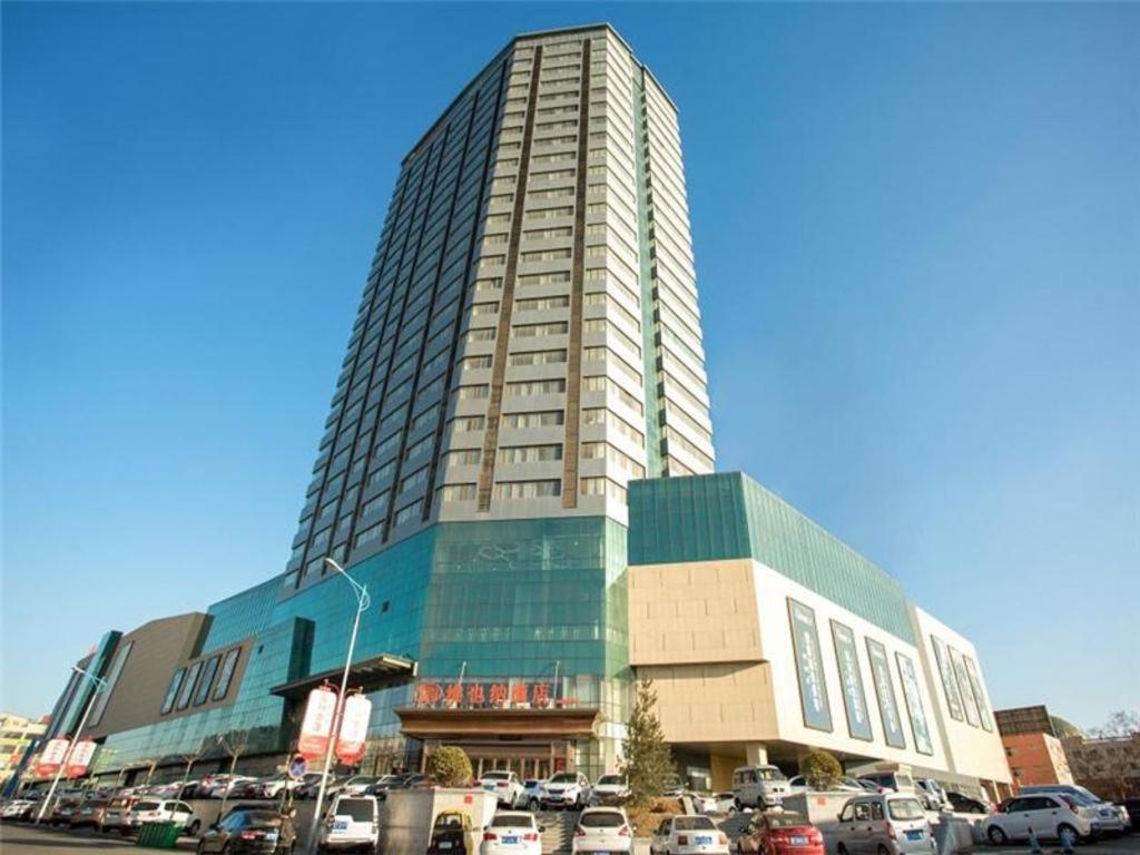 wysoki budynek z samochodami zaparkowanymi na parkingu w obiekcie Vienna Hotel Shandong Laizhou Langhu International Plaza w mieście Laizhou