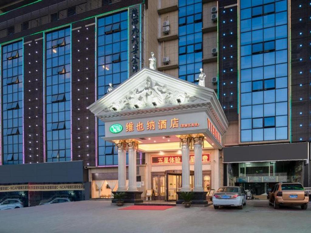 budynek z samochodami zaparkowanymi przed nim w obiekcie Vienna Hotel Shaanxi Ankang Jiangnan w mieście Kuan-miao